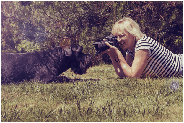 A lady taking a photo  of a Giant Schnauzer