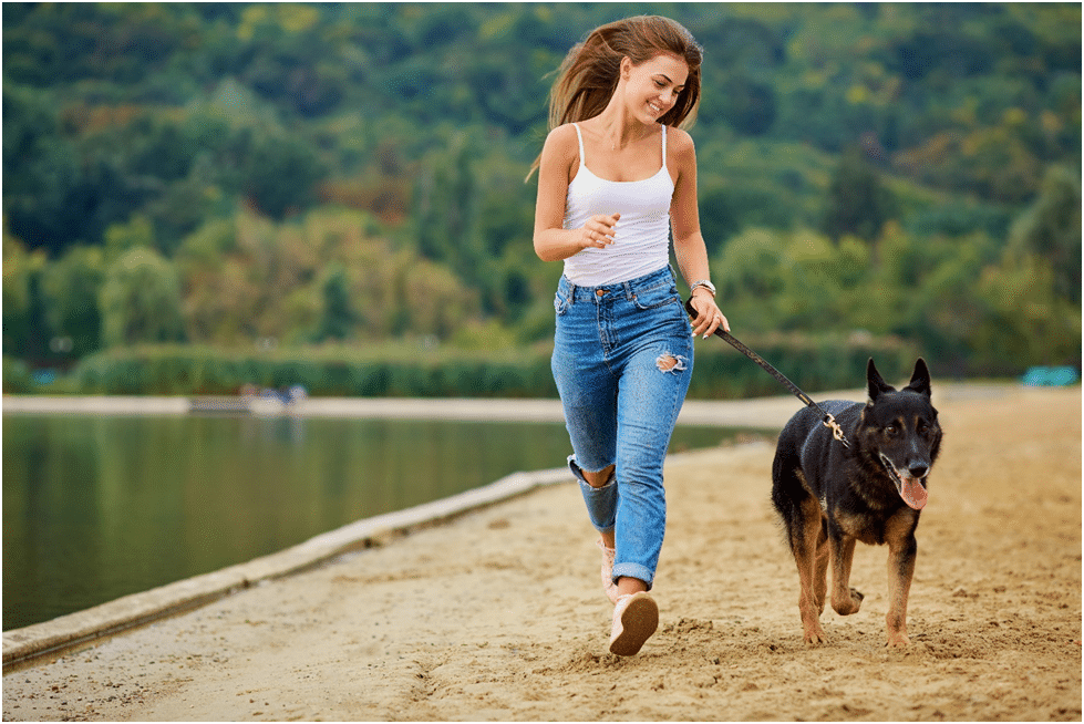 A girl and his German Shepherd dog running on sand